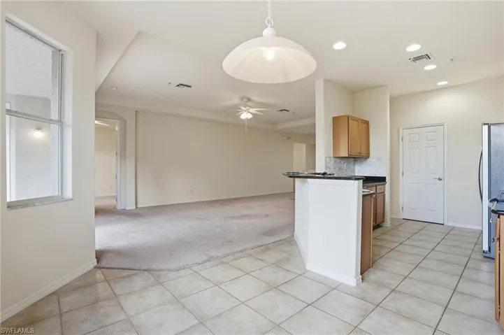 Kitchen featuring light carpet, decorative light fixtures, open floor plan, ceiling fan, and a peninsula