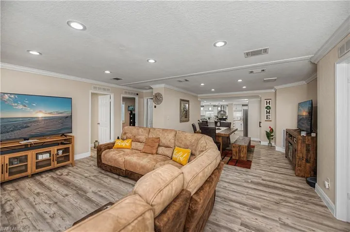 Living area featuring light wood-type flooring, crown molding, recessed lighting, and a textured ceiling