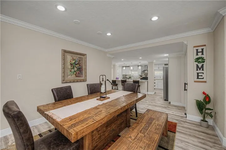 Dining space with light wood finished floors, crown molding, and recessed lighting