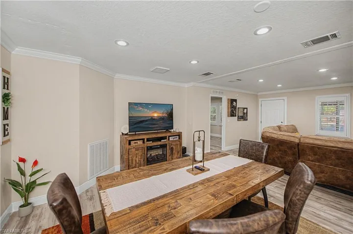 Dining space with light wood-style flooring, ornamental molding, a fireplace, recessed lighting, and a textured ceiling