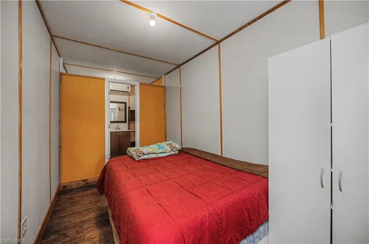 Bedroom featuring ensuite bathroom, wood finished floors, and a wall mounted AC