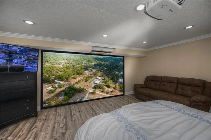 Bedroom featuring wood finished floors, ornamental molding, recessed lighting, a wall mounted AC, and a textured ceiling