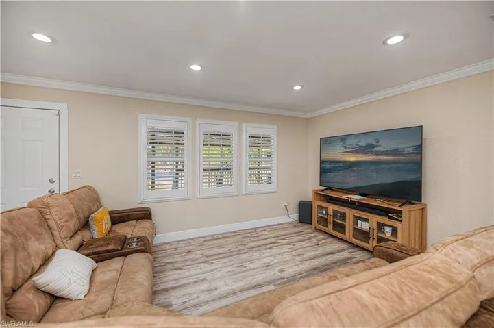 Living area with wood finished floors, crown molding, and recessed lighting