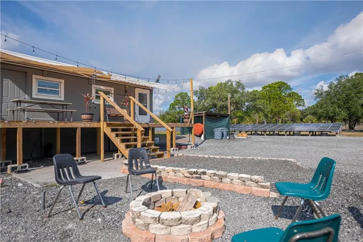 View of yard featuring a wooden deck, a fire pit, a patio, and stairs