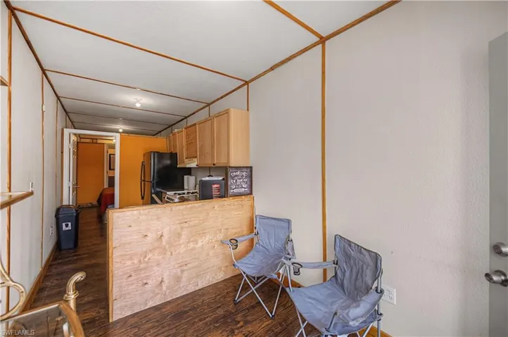 Kitchen featuring dark wood-type flooring, light brown cabinets, freestanding refrigerator, and a peninsula
