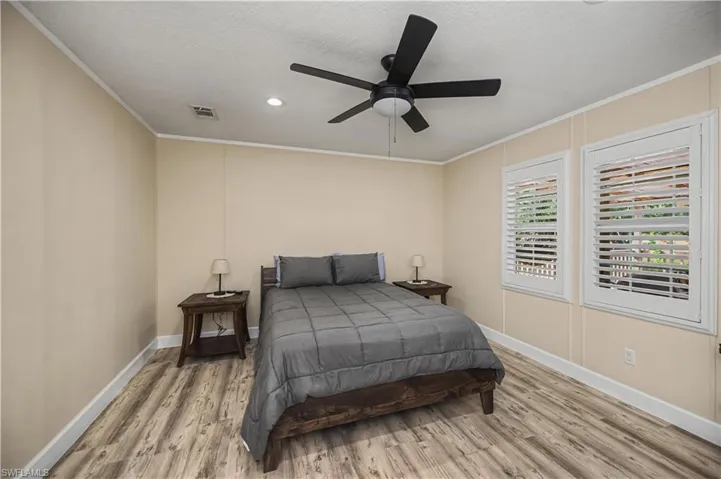 Bedroom featuring light wood-style floors, ornamental molding, ceiling fan, and a textured ceiling