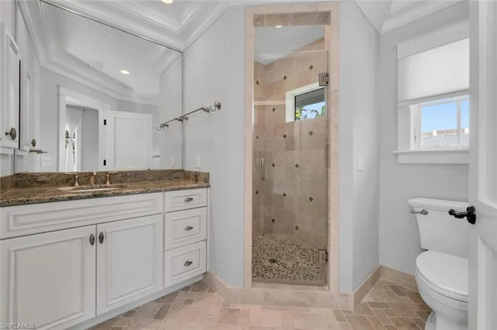 Bathroom with toilet, vanity, a shower with door, and crown molding
