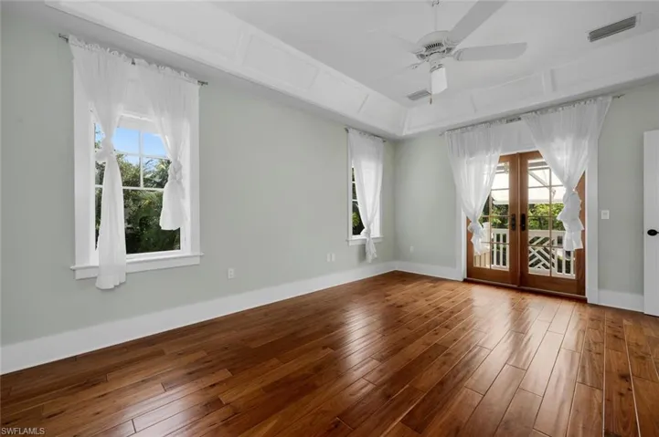 Spare room with ceiling fan, hardwood / wood-style floors, a tray ceiling, and french doors