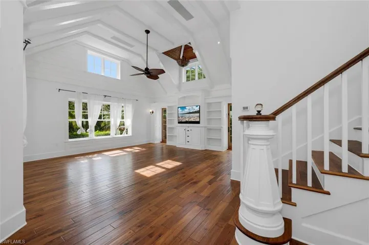 Unfurnished living room featuring high vaulted ceiling, ceiling fan, and dark wood-type flooring