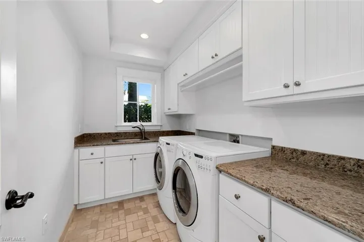 Washroom with cabinets, washer and clothes dryer, and sink