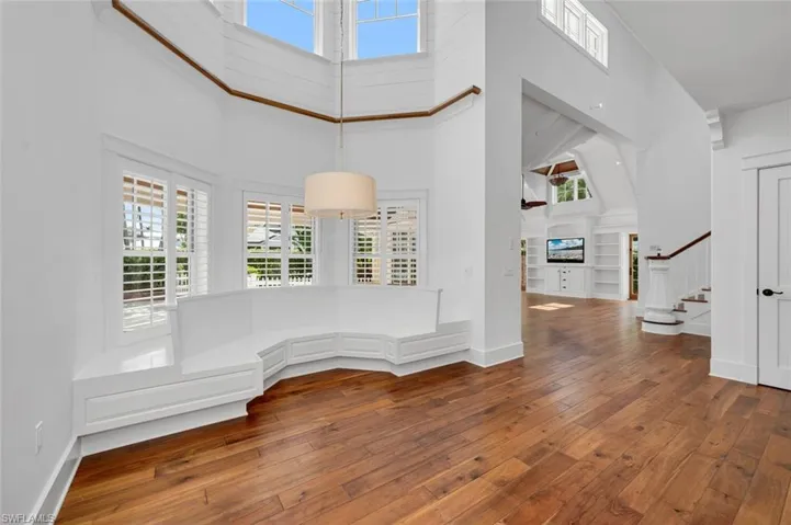 Unfurnished room featuring hardwood / wood-style floors, a high ceiling, and built in shelves