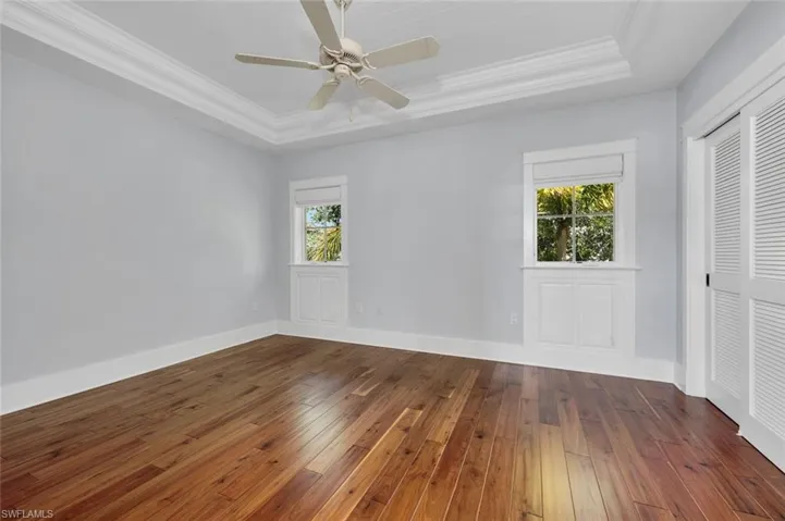 Unfurnished bedroom with ceiling fan, a tray ceiling, and a closet