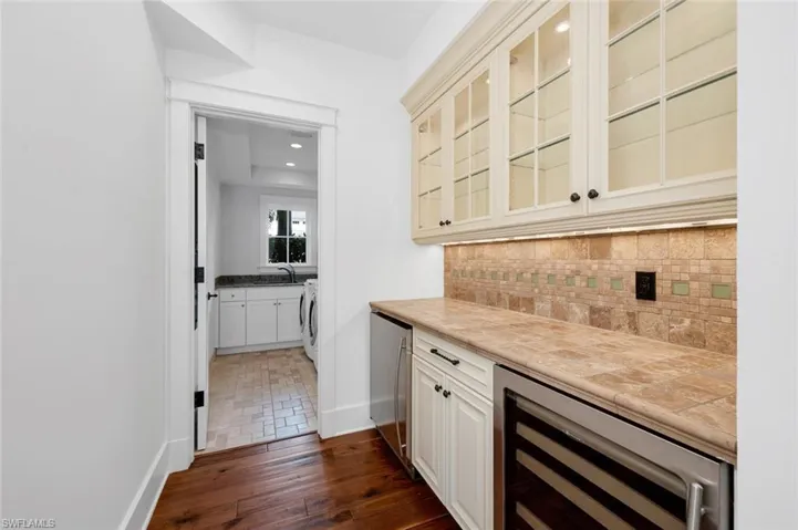 Bar with washer / dryer, backsplash, fridge, beverage cooler, and sink