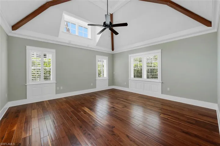 Spare room featuring ceiling fan, plenty of natural light, wood-type flooring, and beam ceiling