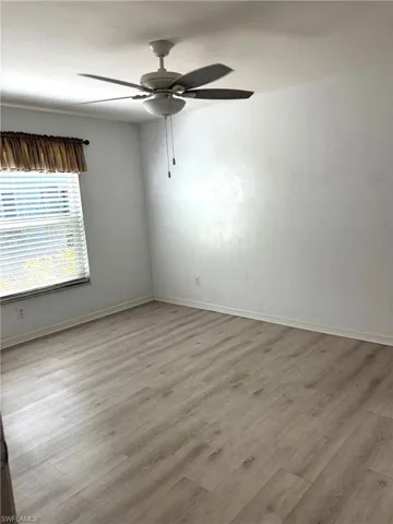 Empty room with ceiling fan and light wood-type flooring