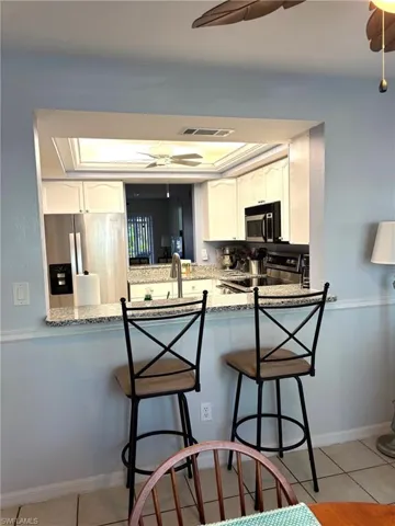 Kitchen featuring kitchen peninsula, appliances with stainless steel finishes, white cabinets, and light tile patterned floors