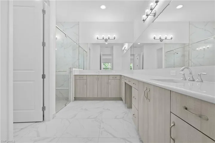 A luxurious primary bathroom featuring dual sinks, modern fixtures, and a large, beautifully tiled walk-in shower