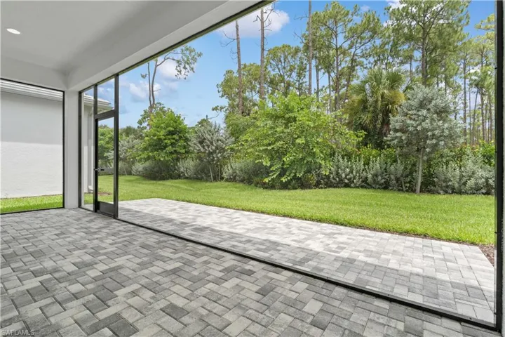 The northern-exposure extended screened patio designed for seamless indoor-outdoor living, offering a peaceful view of the adjacent preserve and wooded area.