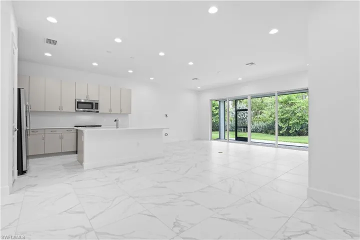 An open-concept great room boasting elegant tile flooring, soaring ceilings, and bright natural light flowing effortlessly into the dining and kitchen areas.