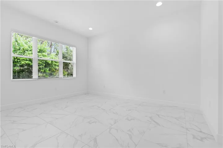 A serene primary bedroom suite complete with high ceilings and large windows looking out to the preserve