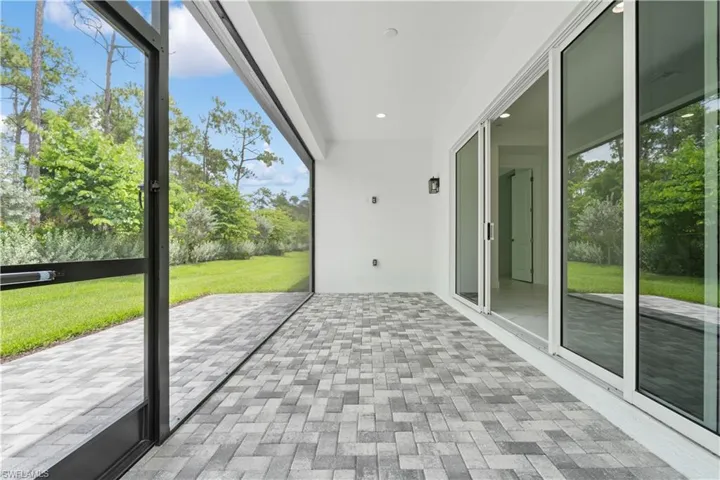 The northern-exposure extended screened patio designed for seamless indoor-outdoor living, offering a peaceful view of the adjacent preserve and wooded area.
