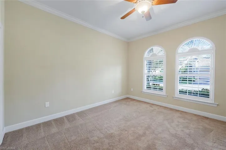 Spare room featuring light colored carpet, plenty of natural light, crown molding, and ceiling fan