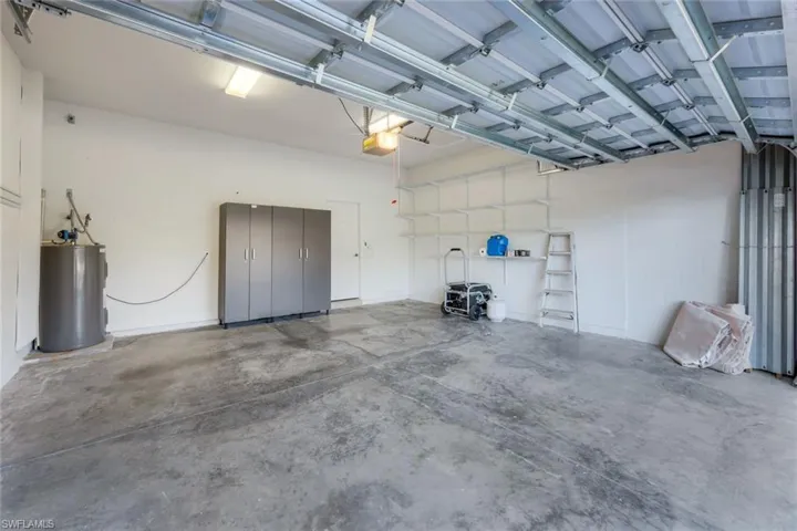 Garage featuring electric water heater and a garage door opener