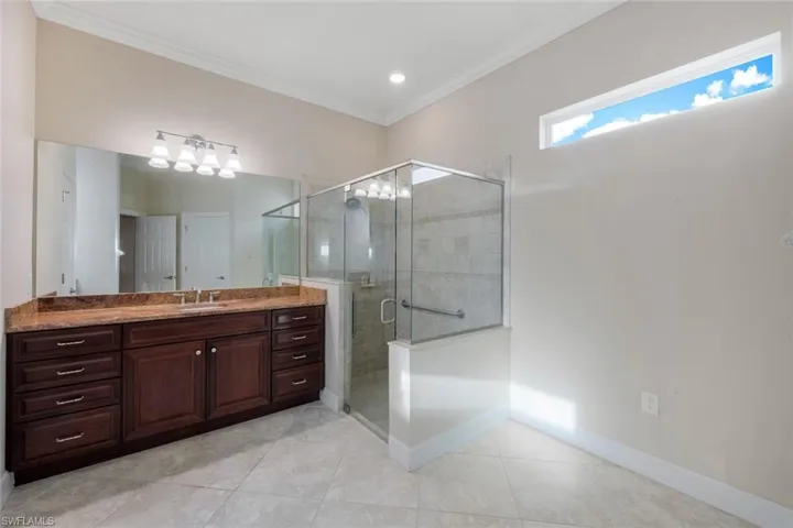 Bathroom featuring tile patterned floors, vanity, ornamental molding, and walk in shower