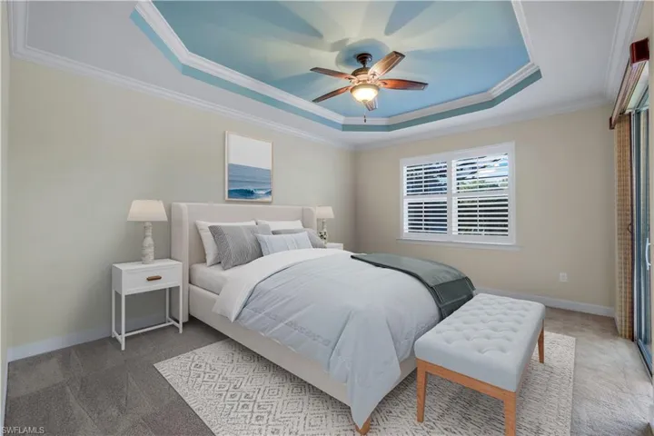 Bedroom with ceiling fan, ornamental molding, carpet, and a raised ceiling