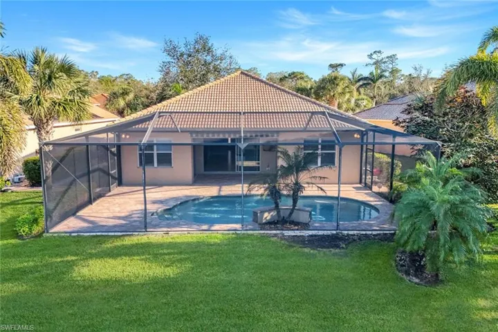 Back of property, a patio area, and a lawn