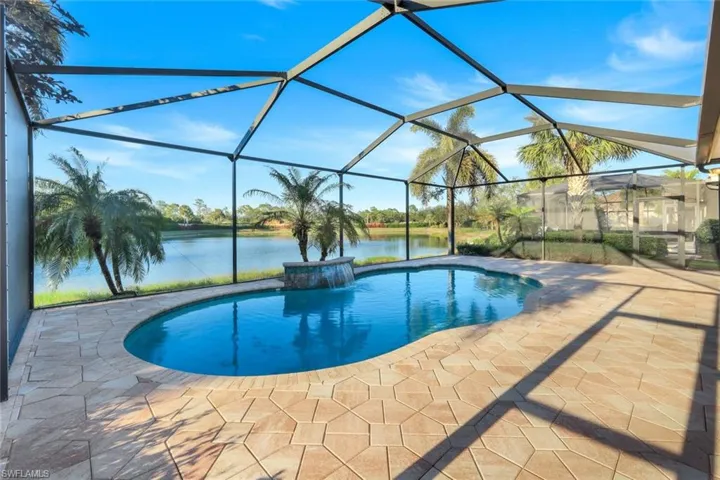 View of pool featuring pool water feature, a water view, a patio area, and a lanai