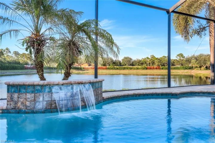View of swimming pool with pool water feature, a water view, and glass enclosure