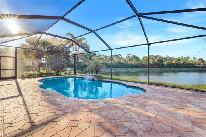 View of swimming pool with pool water feature, a water view, a patio, and a lanai