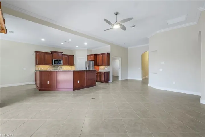Kitchen with ceiling fan, tasteful backsplash, appliances with stainless steel finishes, light tile patterned floors, and ornamental molding