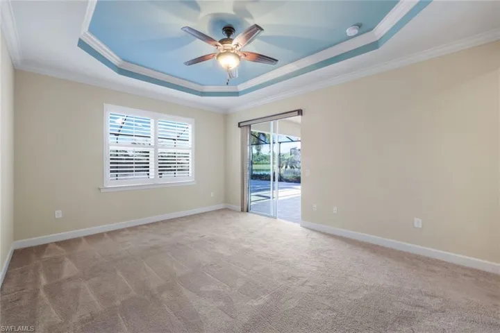 Carpeted Master Bedroom with a raised ceiling, crown molding, and ceiling fan
