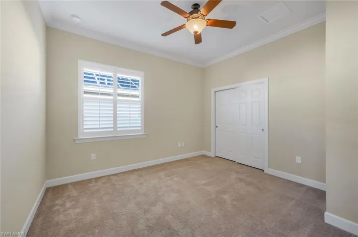 Unfurnished bedroom featuring light carpet, a closet, ceiling fan, and ornamental molding