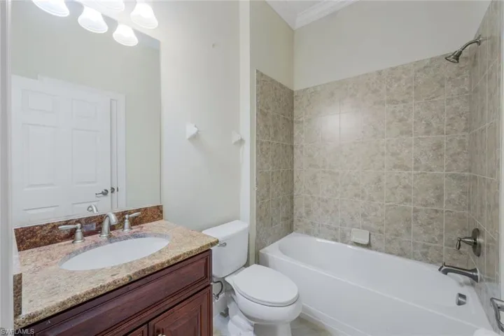 Full bathroom with toilet, vanity, ornamental molding, and tiled shower / bath