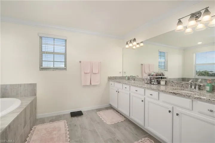 Double vanity with white cabinetry and granite countertops, featuring dual sinks and individual faucets