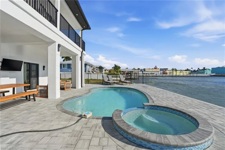 View of pool featuring a balcony, a patio area, and a pool with connected hot tub Virtually Edited