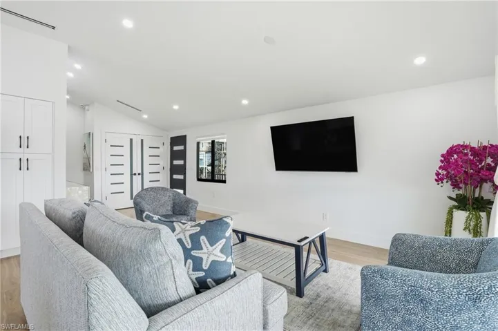 Living area with vaulted ceiling, light wood finished floors, and recessed lighting Virtually Edited