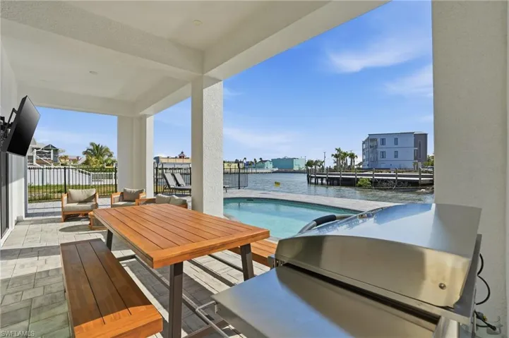 Outdoor pool featuring a patio, area for grilling, an outdoor hangout area, outdoor dining area, and a water view