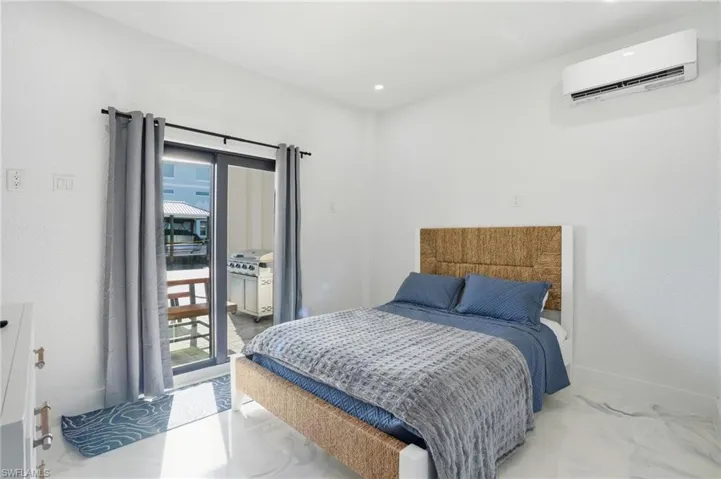 Bedroom with a wall mounted air conditioner, marble look tile flooring, recessed lighting, and access to exterior virtually edited