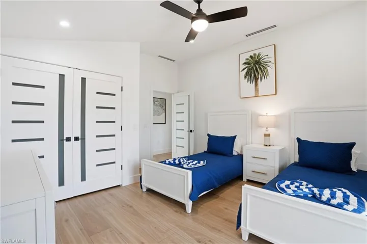 Bedroom featuring light wood-style floors, a ceiling fan, vaulted ceiling, and a closet virtually edited