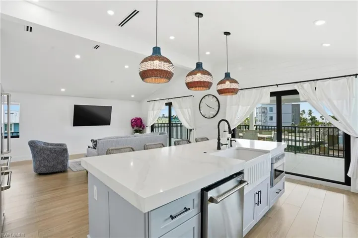 Kitchen with light stone counters, a kitchen Virtually Edited with sink, open floor plan, light wood-style flooring, and hanging light fixtures