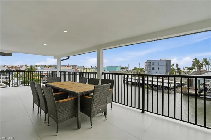 Balcony featuring outdoor dining area, a residential view, and a water view virtually edited
