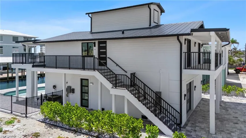 Back of house with stairs, metal roof, a patio area, and fence- Virtually Edited