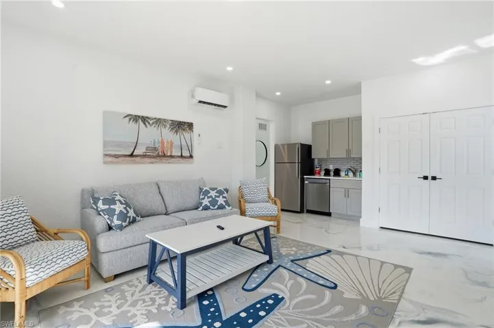 Living room featuring recessed lighting, a wall mounted AC, and light Epoxy floors Virtually Edited