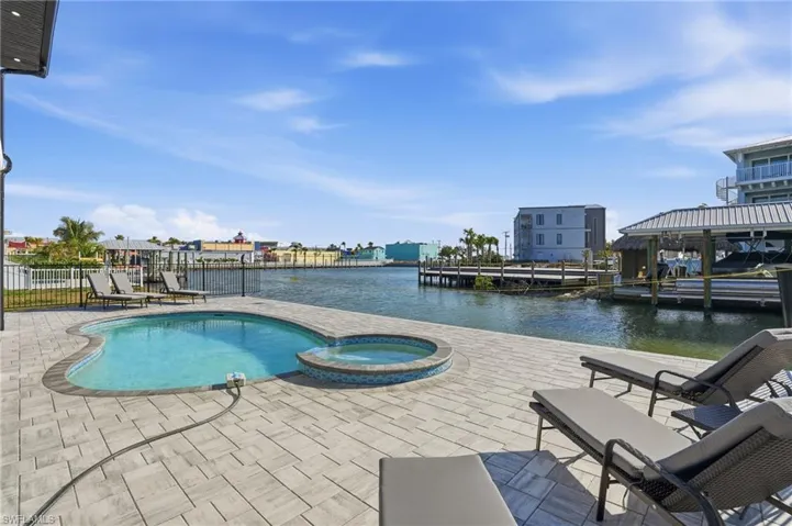 View of swimming pool with a pool with connected hot tub, a patio, and a water view