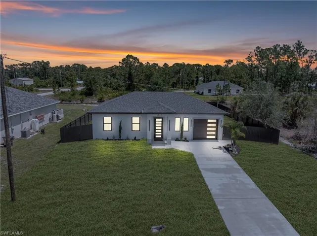 View of front facade with concrete driveway, an attached garage, stucco siding, central air condition unit, and a shingled roof