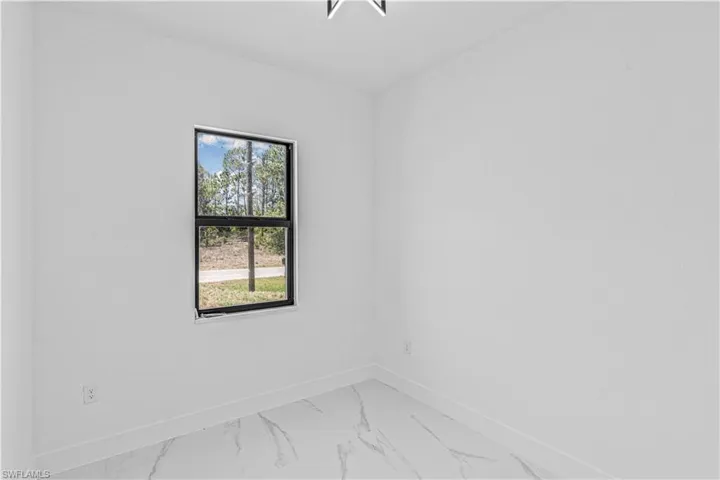 Unfurnished room featuring baseboards and light marble finish floors